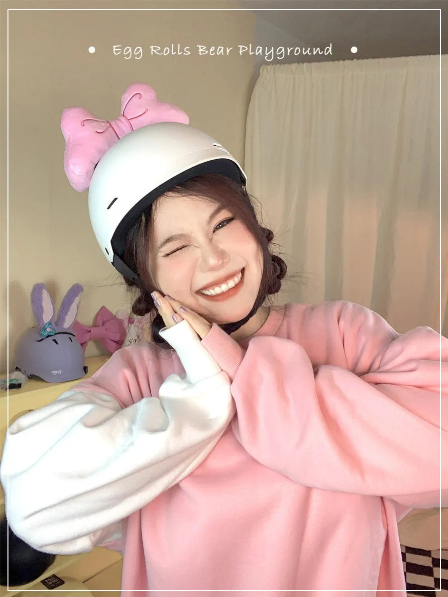 A soft plush bow tie helmet decoration shown in red, peach pink, and rose pink colours.