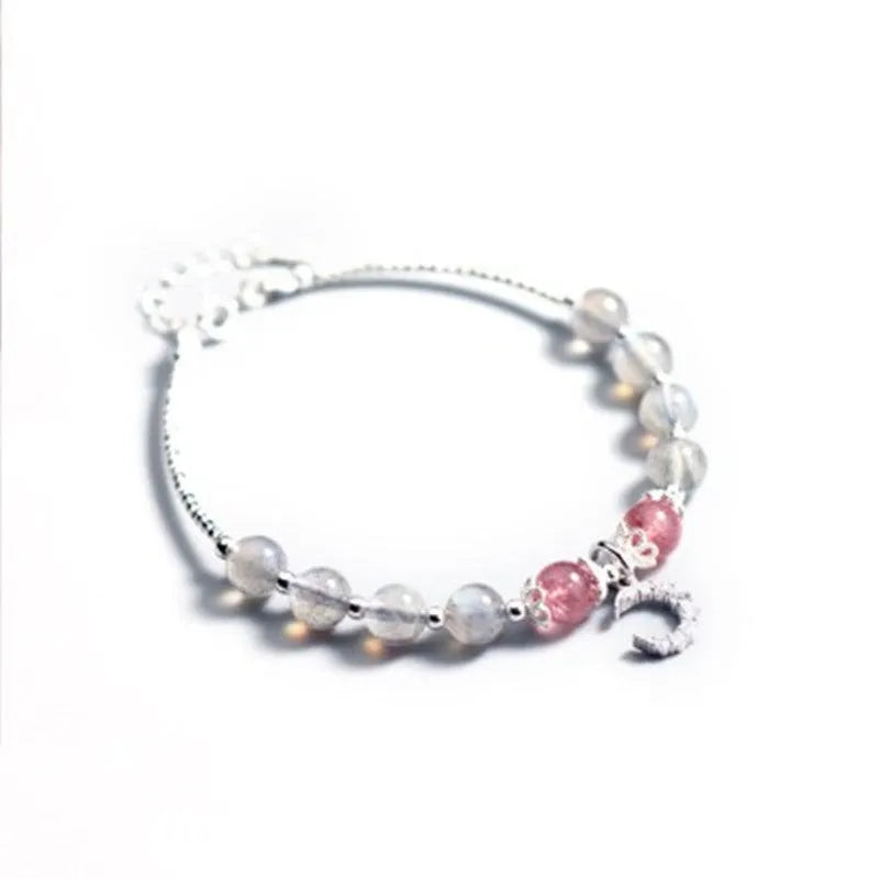 Handmade adjustable moonstone bracelet with silver crescent moon charm and crystal bead on a wrist.