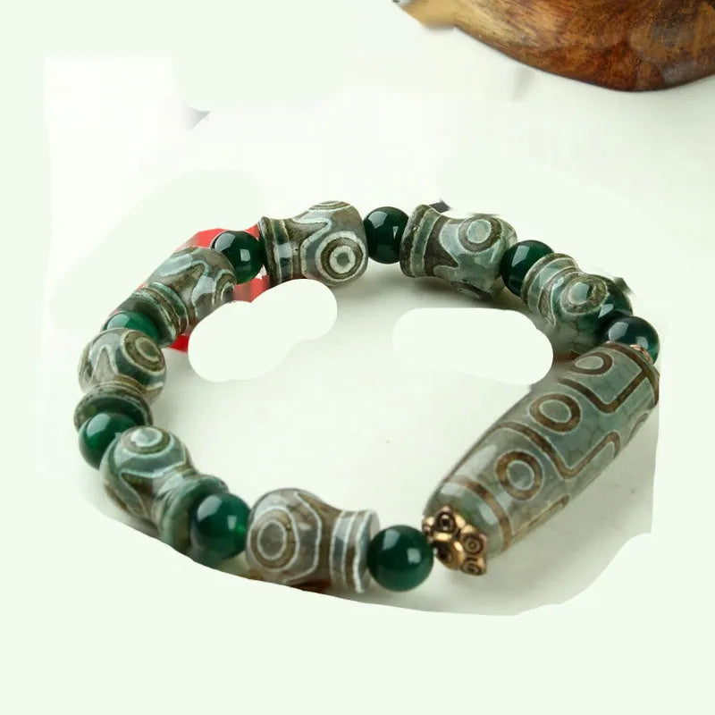 Distressed agate Tibetan bead bracelet with three-eye motifs and polished finish.