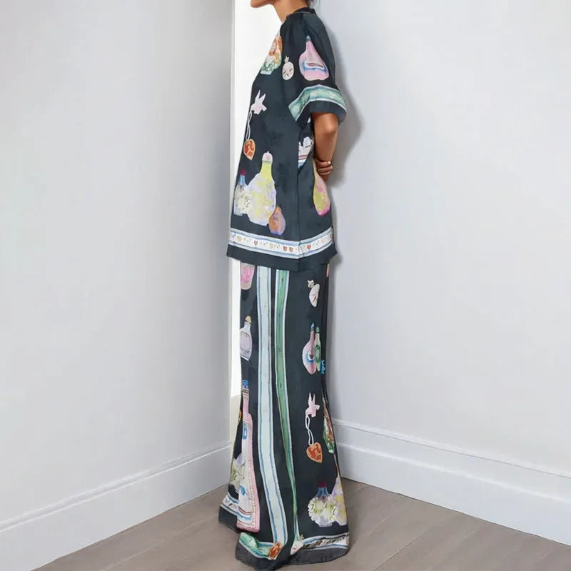 Black women's cardigan and pants set with cartoon animation pattern, shown laid flat.
