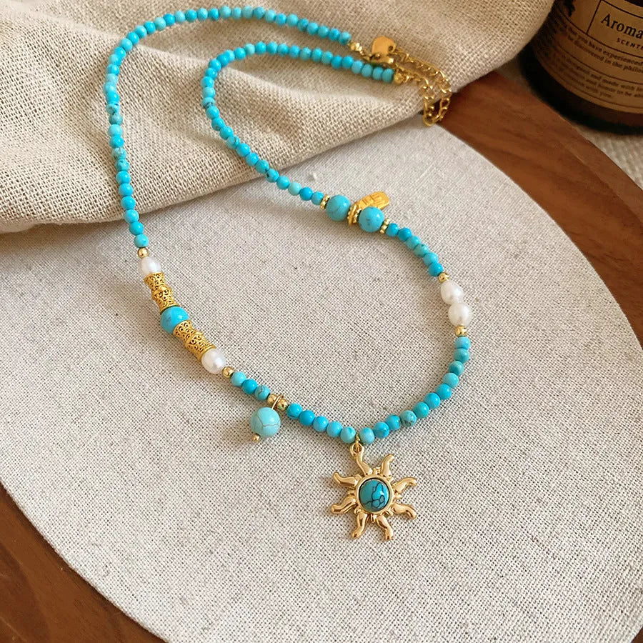 Freshwater pearl sun necklace with blue stone pendant on a gold-tone adjustable chain.