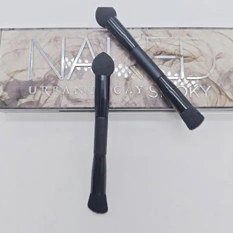 Double-headed makeup brush with black sponge end and pointed brush end on wooden handle
