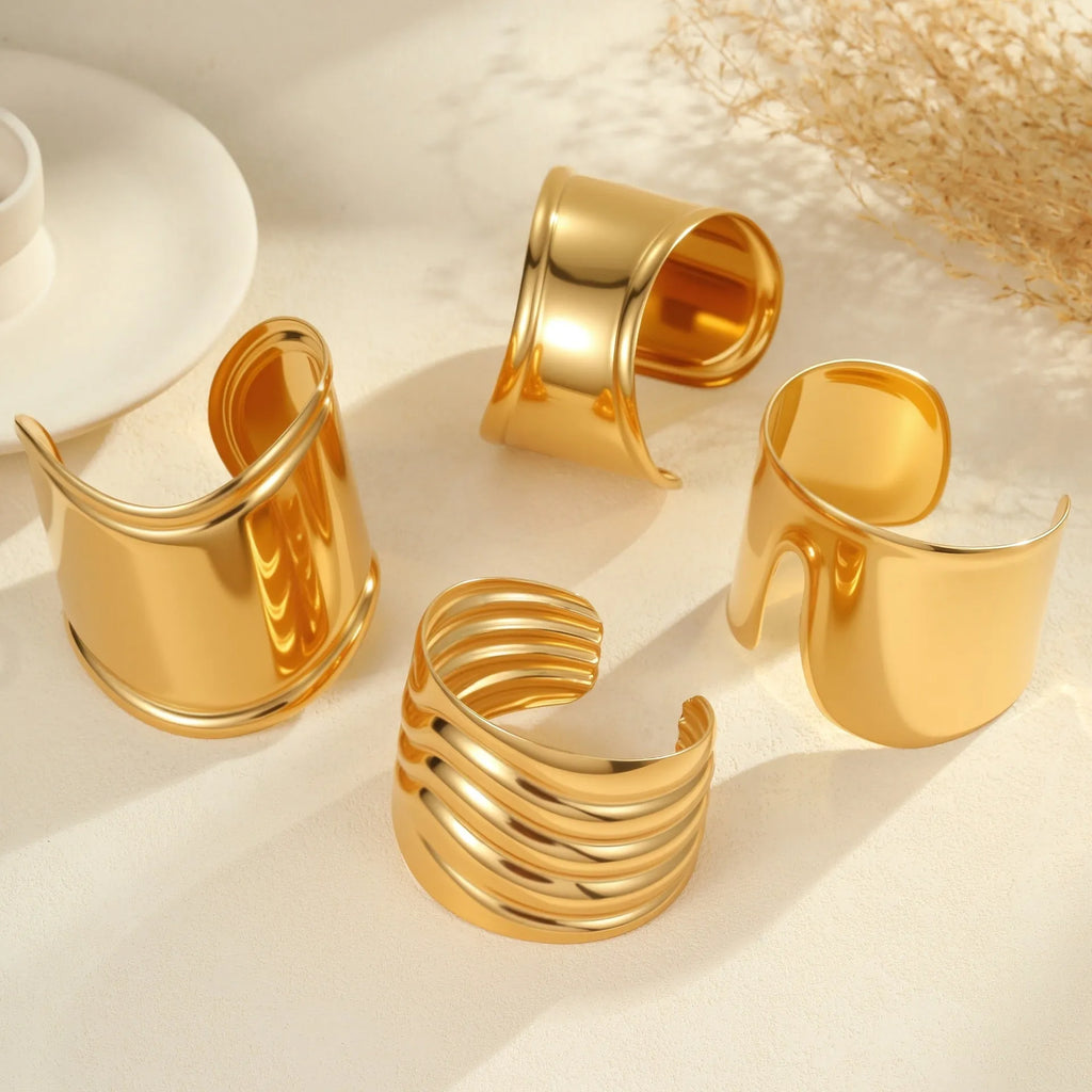 Gold-plated stainless steel bracelet with asymmetric geometric wave design and wide opening.
