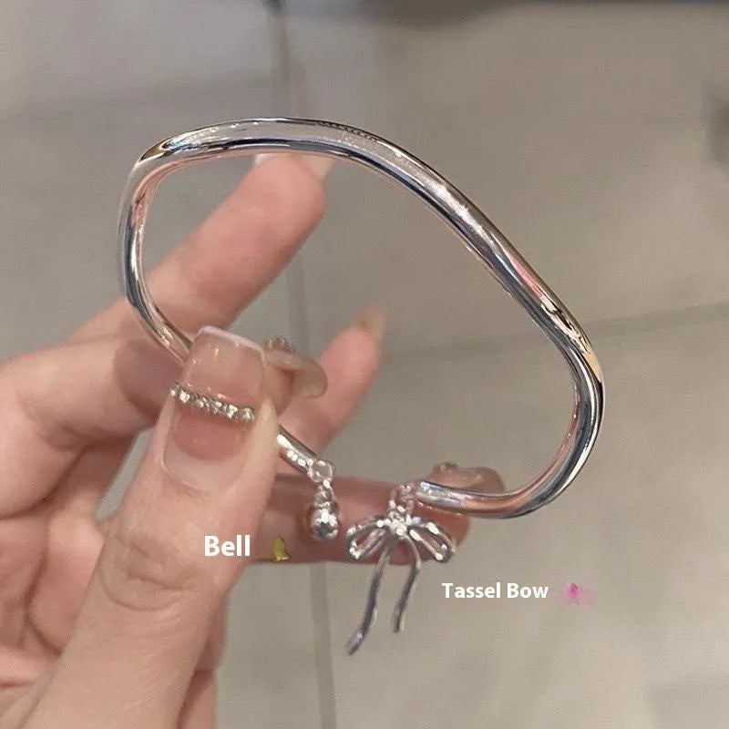 Silver bow adjustable bracelet with bell opening mechanism on wrist