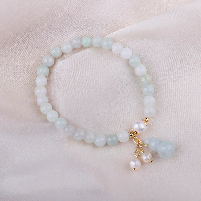 Chinese style gourd design jade bracelet for women with a pearl accent on a white background.