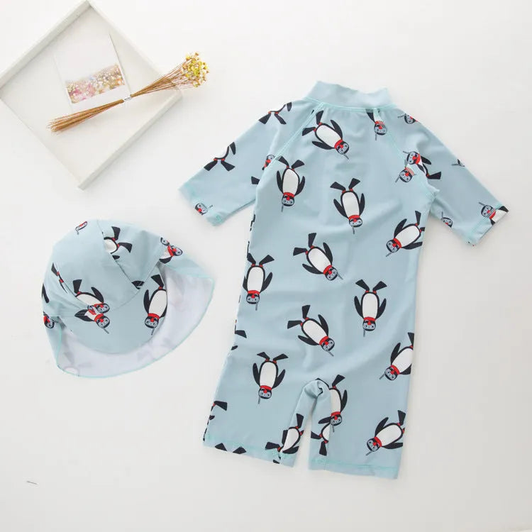 Boy's long sleeve penguin print swimsuit set with matching swimming cap on a white background.