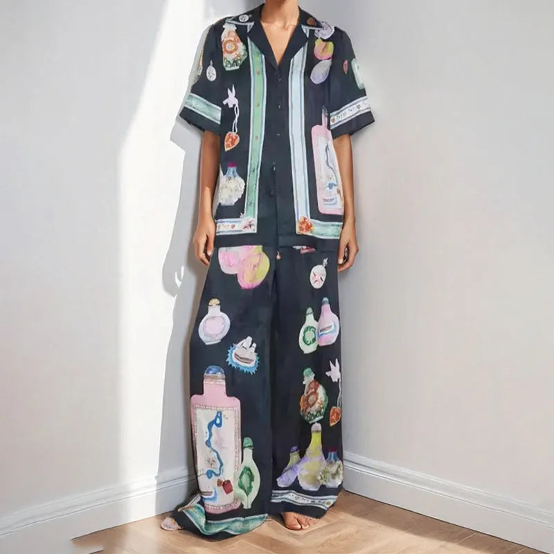 Black women's cardigan and pants set with cartoon animation pattern, shown laid flat.