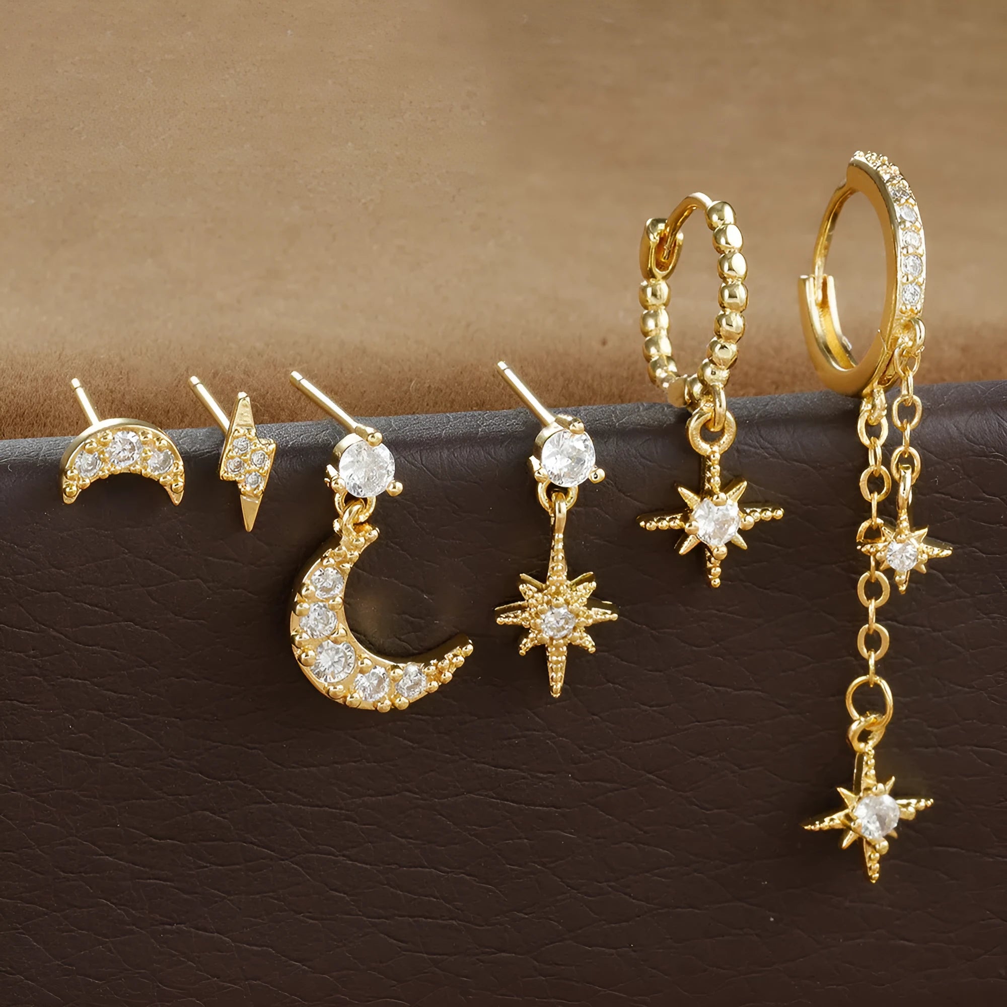 Six pairs of gold chain tassel earrings with zircon stones arranged in display