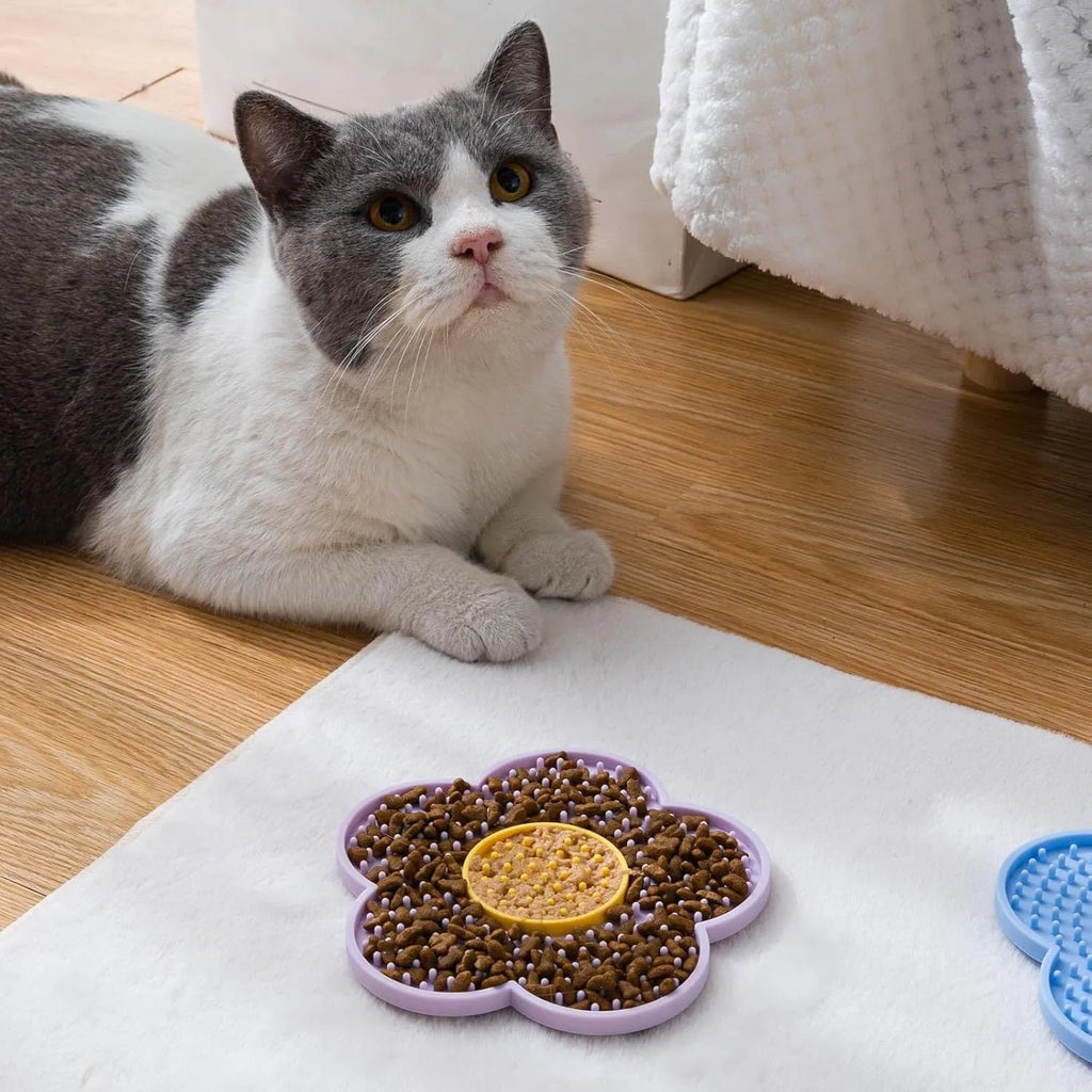 Flower-shaped blue silicone pet licking mat with suction cups on a smooth surface.