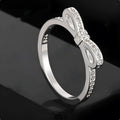 Silver-coloured bow-shaped ring with clear rhinestone embellishments on a white background