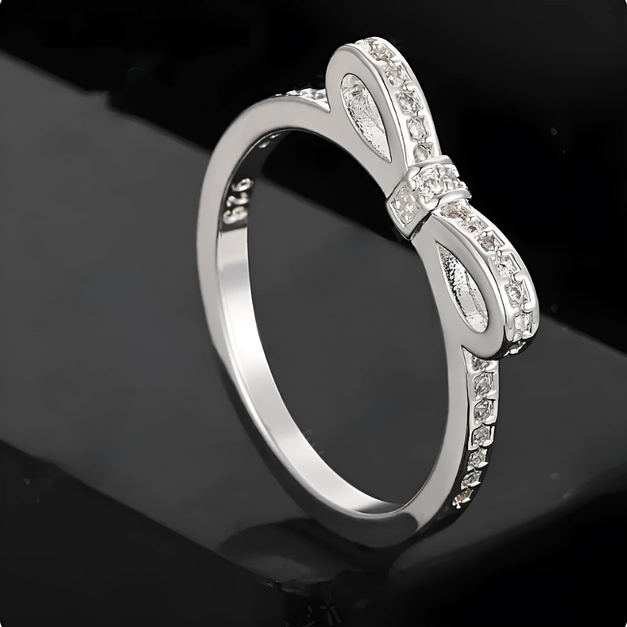 Silver-coloured bow-shaped ring with clear rhinestone embellishments on a white background