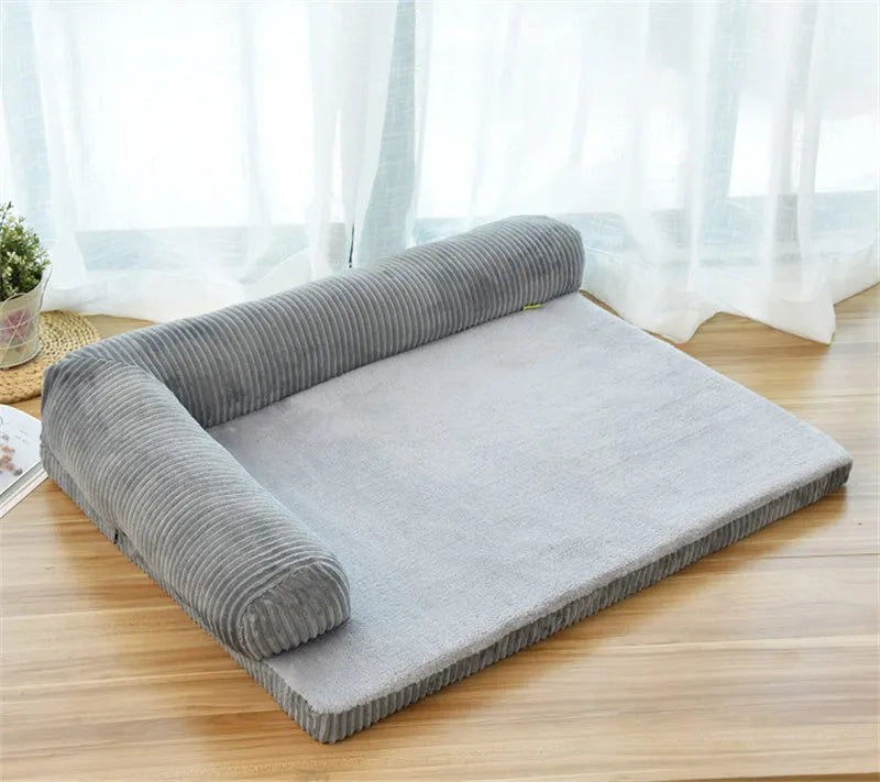 Corduroy pet sofa dog bed with bolster, shown in a grey colour on a wooden floor.