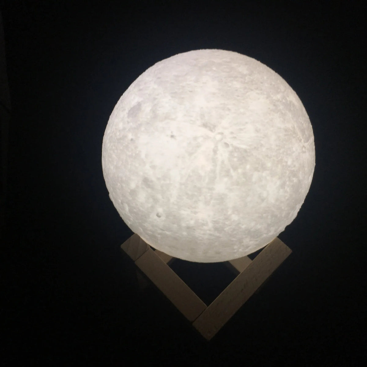 3D printed white moon lamp with detailed craters on a wooden stand, showing touch ring at base.