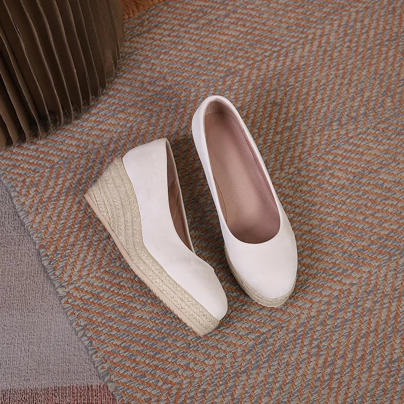 Black wedge heel pumps with thick rope-textured sole and shallow mouth opening.