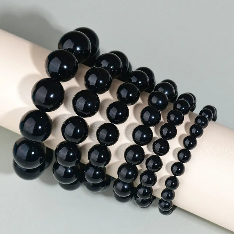 Hand-woven round obsidian crystal bracelet in ethnic style on a wrist, showing colour and bead size options.