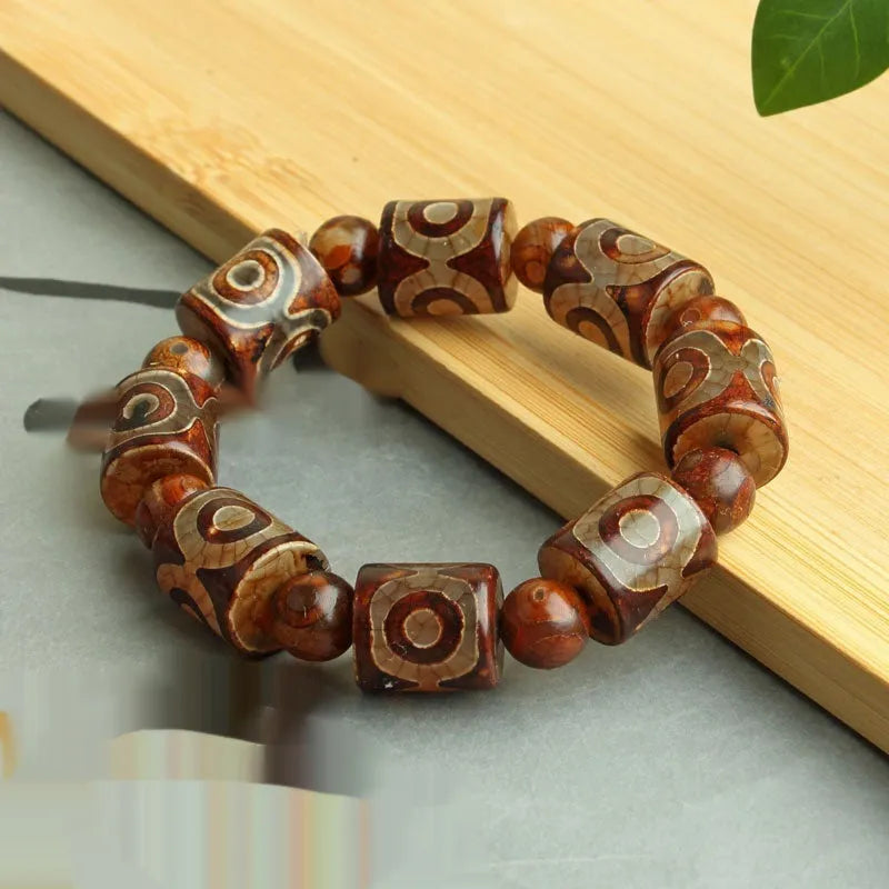 Distressed agate Tibetan bead bracelet with three-eye motifs and polished finish.