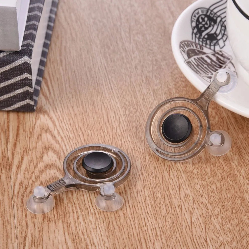 A pair of clear mini joysticks with black caps next to a drawstring bag, for mobile phone touch screen games.