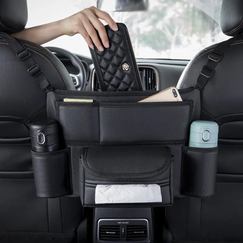 Black leather car seat hanging organiser bag holding a tissue box between vehicle front seats.