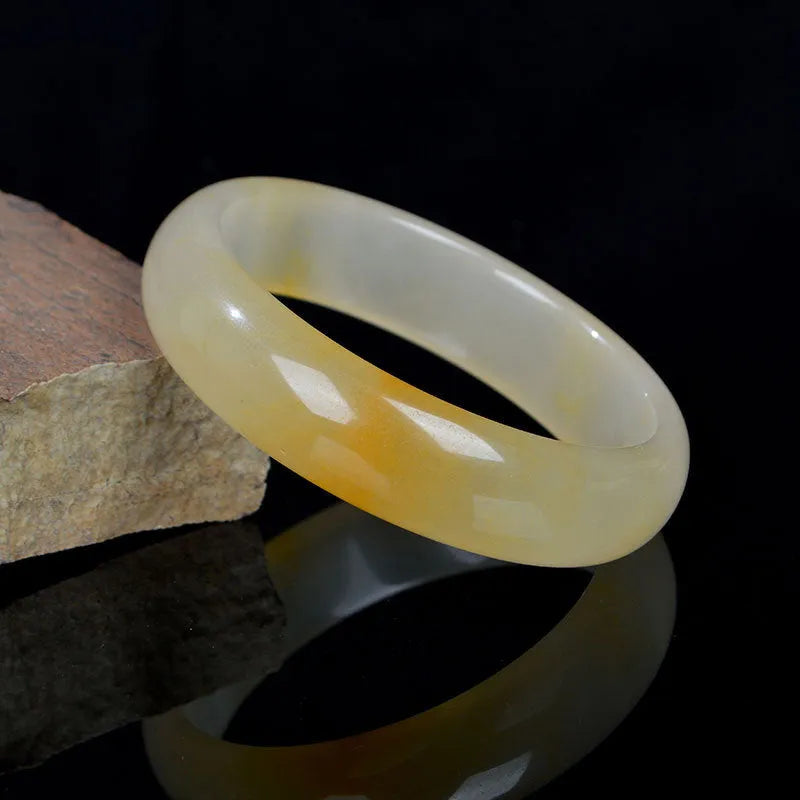 Natural light jade bracelet with a polished finish on a wrist, showing its Chinese style.