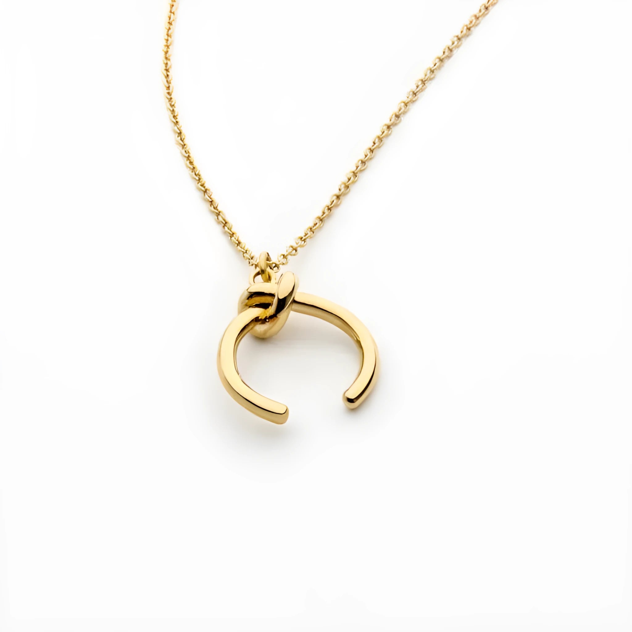 Close-up of a geometric copper pendant necklace with a gold electroplated finish on an adjustable cross chain.