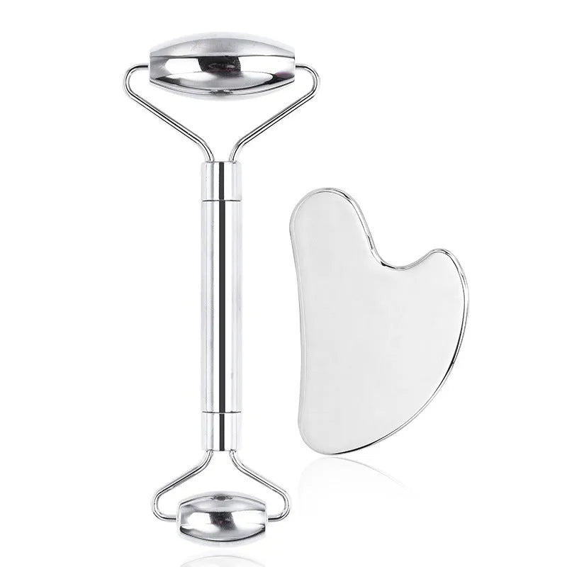 Stainless steel facial massage set showing a double-ended acupuncture pen with pointed tip and heart roller, plus a gua sha scraping plate.