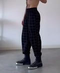 Men's plaid pattern trousers featuring an apron-style front fastening.