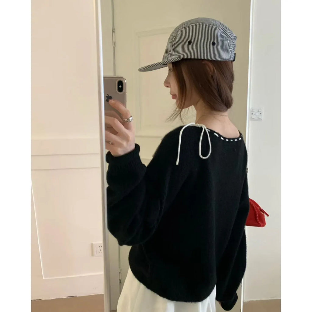 Women's loose-fitting black knitwear pullover jumper on a hanger.