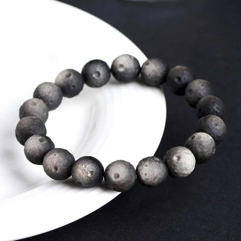 Natural obsidian crater ball bracelet showing distinctive grinding texture on beads
