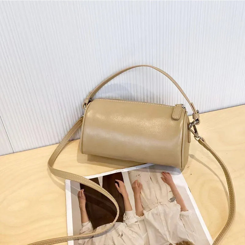 Soft genuine leather cylindrical crossbody bag for mobile phones in brown colour with visible stitching.