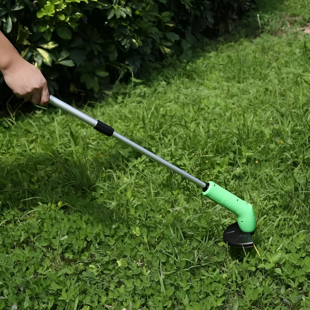 Cordless handheld lawn trimmer with extension pole and protective debris shield on a lawn.