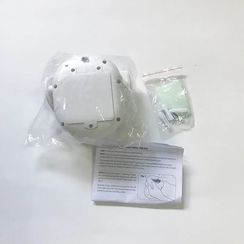 White Atomic Angel induction light unit on a surface, showing its compact 13.3cm by 9.8cm by 15.8cm dimensions.