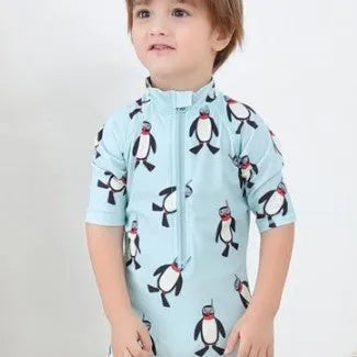 Boy's long sleeve penguin print swimsuit set with matching swimming cap on a white background.
