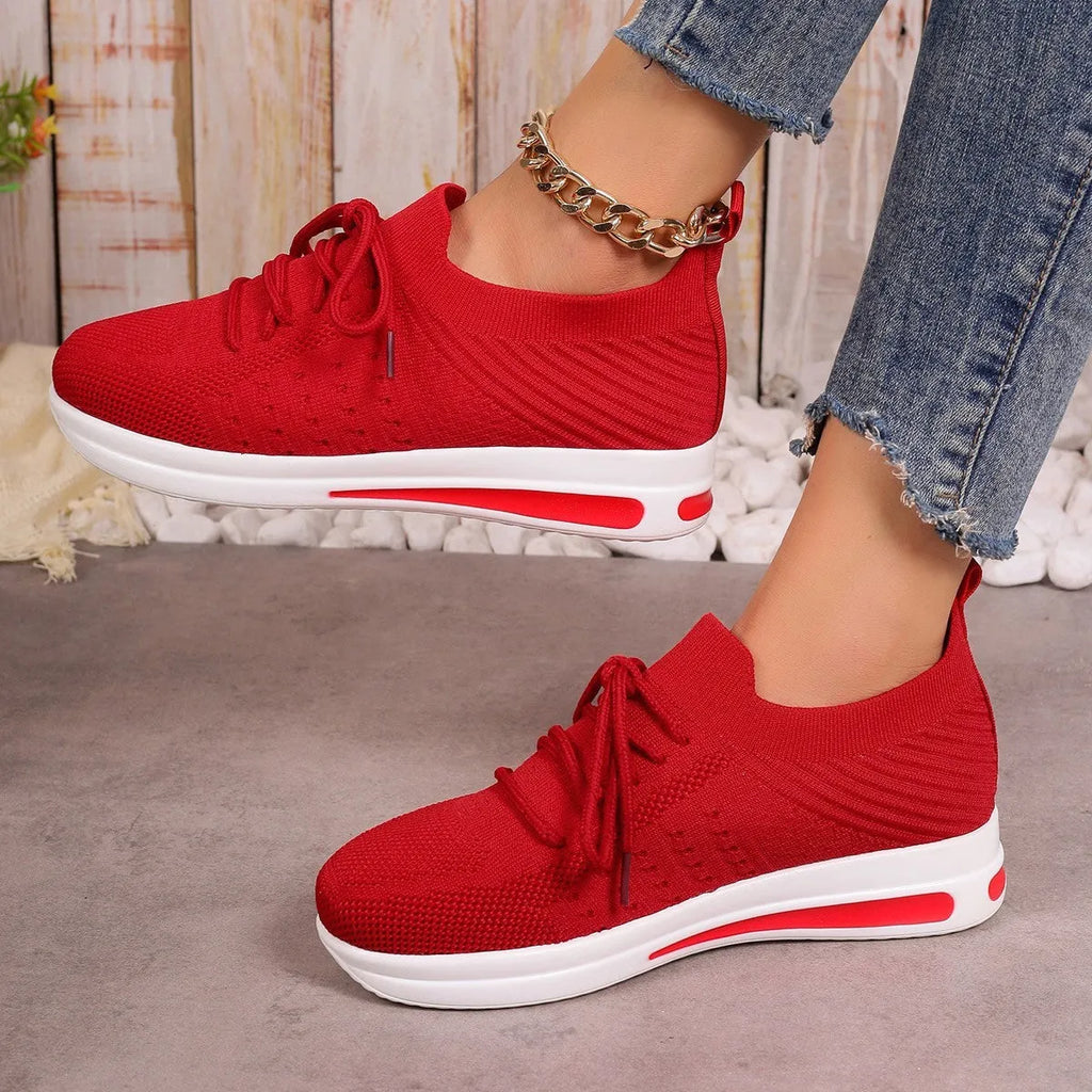Women's low-top red casual sneakers with round toe and white lace-up front on a plain background.