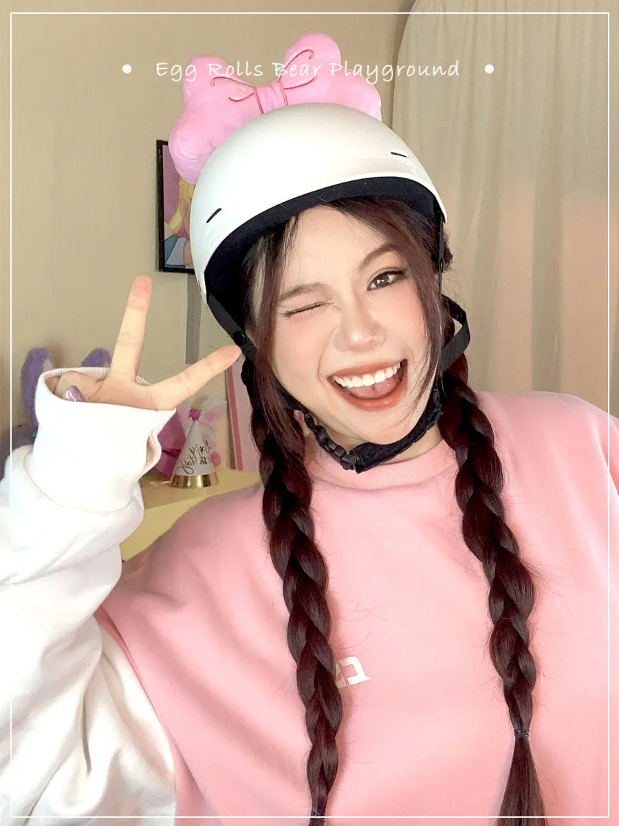 A soft plush bow tie helmet decoration shown in red, peach pink, and rose pink colours.