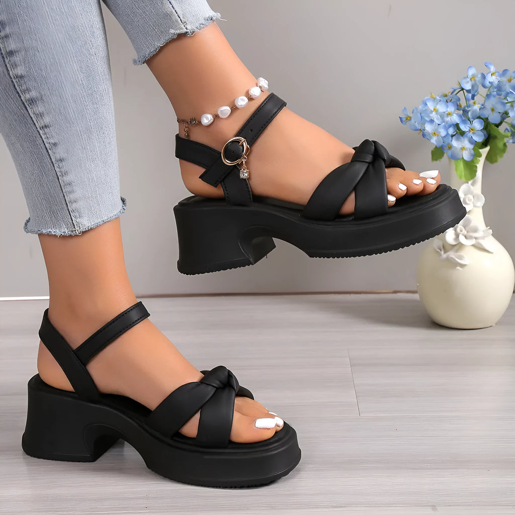 Black wedge heel slippers with round toe and a single button fastening on the strap.