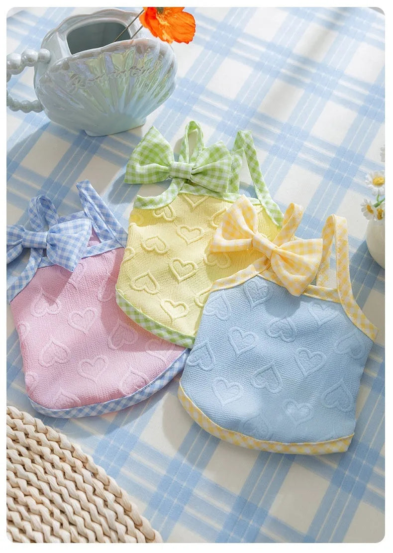 Small dog wearing a blue elastic vest with a heart texture pattern and bow suspenders.