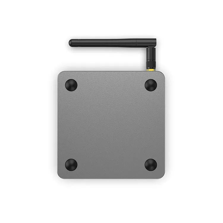 Android smart TV set-top box with voice control remote on a table next to a television.