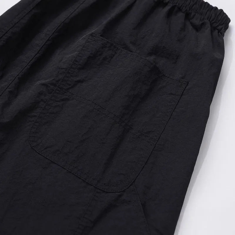 Black baggy paratrooper pants with an elastic waistband on a neutral background.