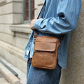 Men's brown genuine leather crossbody shoulder bag with visible stitching and a solid colour design.