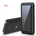 Black portable power bank with wireless Qi charging pad, three USB ports, and LED flashlight