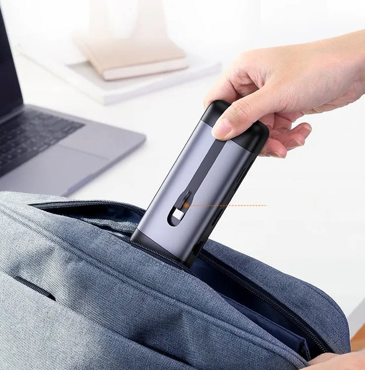 USB-C dock expansion adapter with short cable next to a laptop, showing HDMI, USB, and Ethernet ports.
