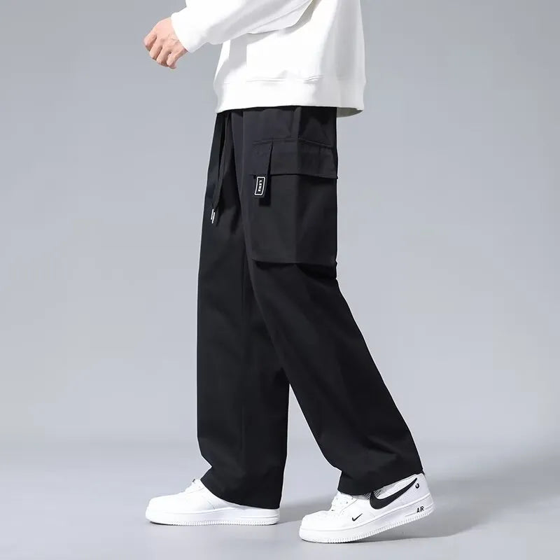 Boy wearing army green straight leg cargo pants with large pockets and a drawstring waist.