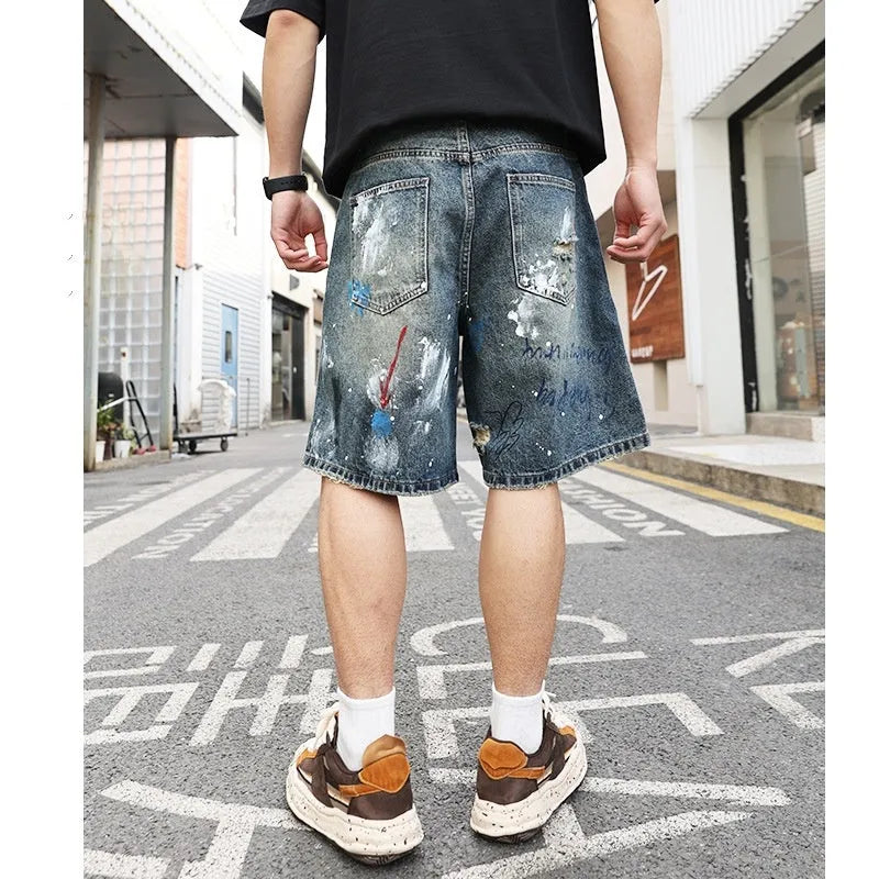 Blue distressed denim shorts with graffiti detail and ripped styling on mannequin
