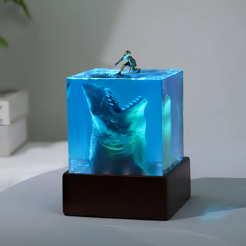 Clear epoxy resin ornament with shark surfing scene inside, on a plastic lamp holder base.