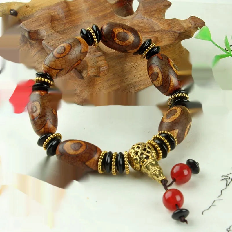 Distressed agate Tibetan bead bracelet with three-eye motifs and polished finish.