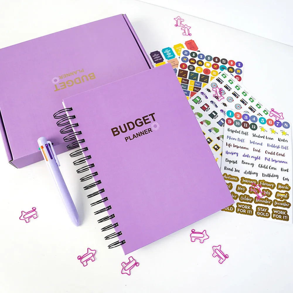 Purple coil-bound budget planning notebook with pen, stickers, and paper clips for financial organisation