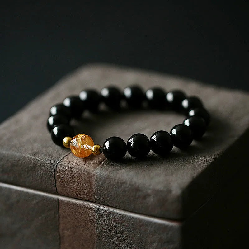 Geometric obsidian and white crystal unisex bracelet with a golden dragon bead on a wrist.