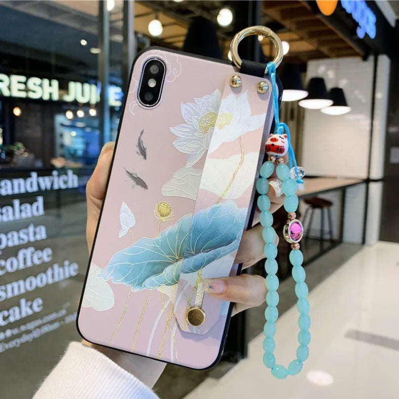 Rose flower design wrist strap case for Apple iPhone on a table.