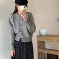 Women's light blue cardigan sweater with white bow pearl buttons fastened.