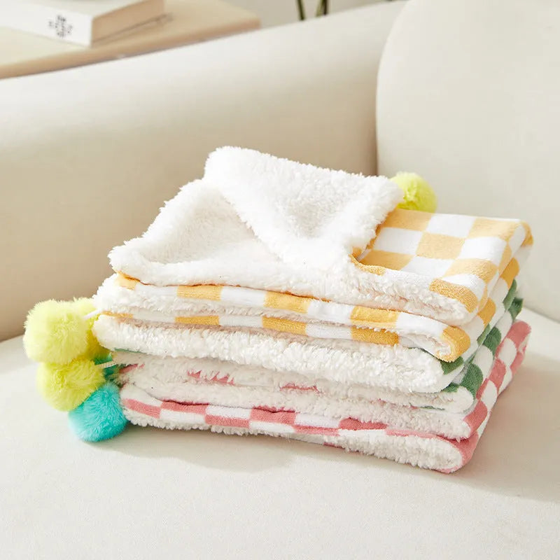 Plush pet blanket with bright plaid pattern and fur ball decorations for cats and dogs